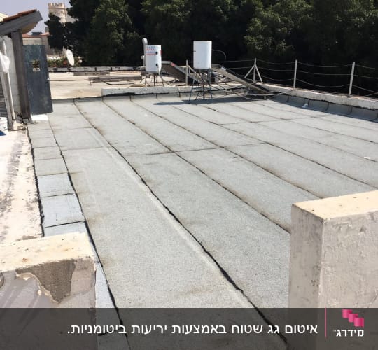 גג עם יריעות איטום אפורות ומיכלי מים